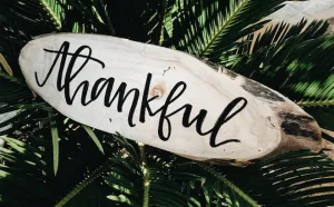 the word “Thankful” written in calligraphy style on a piece of wood