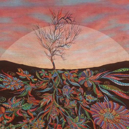 a leafless tree with spreading roots and flowers beneath it
